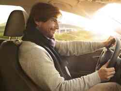 Mann sitzt lächelnd am Steuer eines Fahrzeugs